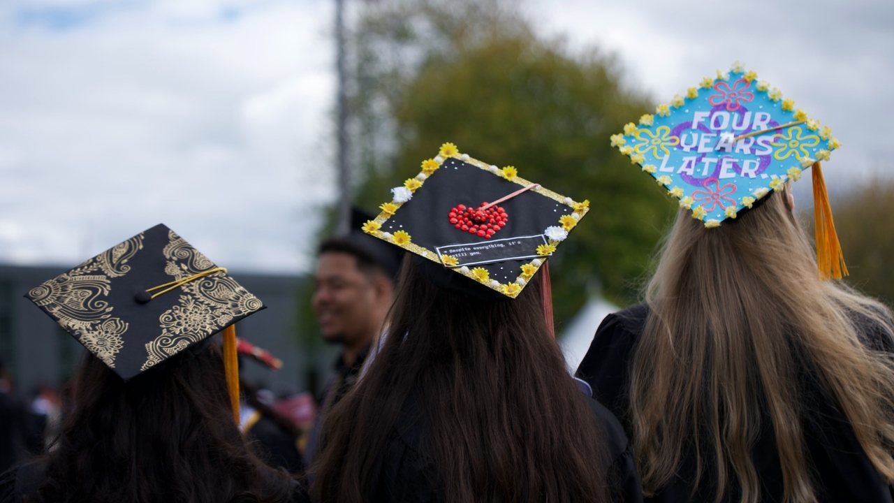 Three graduates with decorated mortarboards are seen from behind at 2026 Undergraduate Commencement
